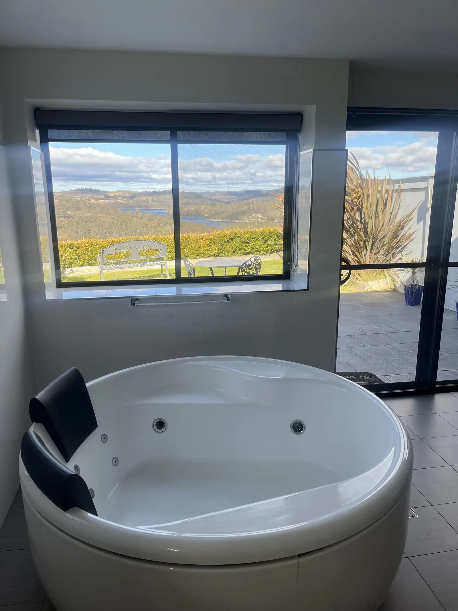 Round spa bath beside a picture window onto the lake and hills