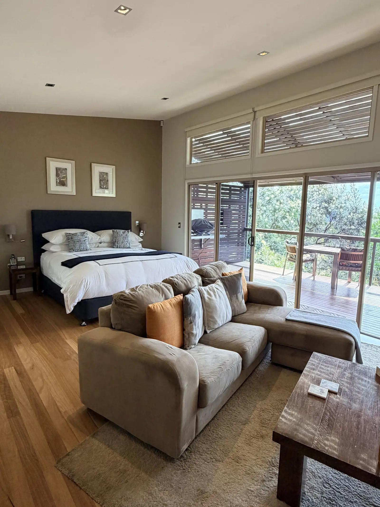 Open-plan bedroom and lounge opening to a deck with bushland views